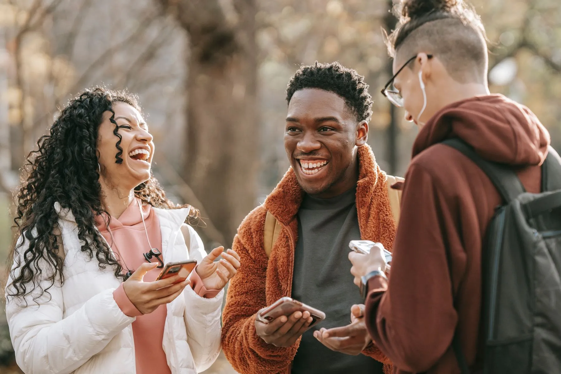 Three friends laughing together in a park