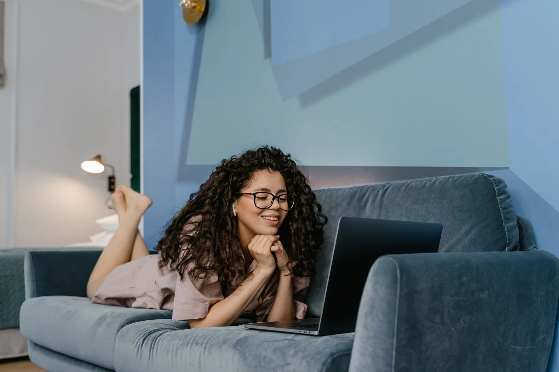 A woman on a video call from her couch, laptop resting on a cushion